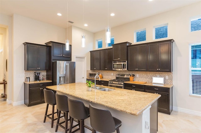 kitchen with light stone countertops, appliances with stainless steel finishes, a breakfast bar, and a sink