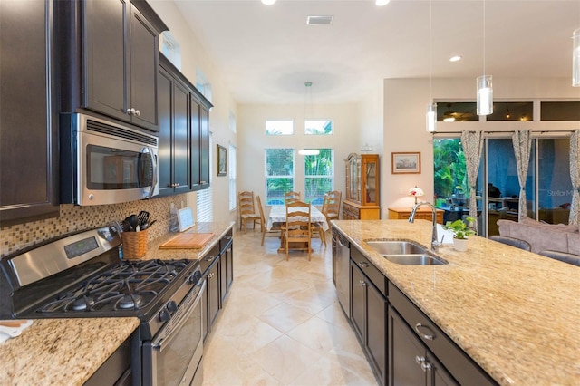 kitchen featuring tasteful backsplash, hanging light fixtures, appliances with stainless steel finishes, and a sink