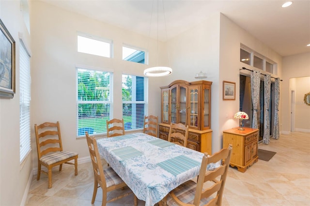 dining area with a high ceiling, recessed lighting, and baseboards