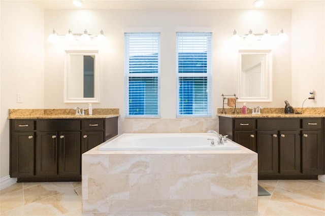 full bathroom featuring a garden tub, two vanities, a healthy amount of sunlight, and a sink