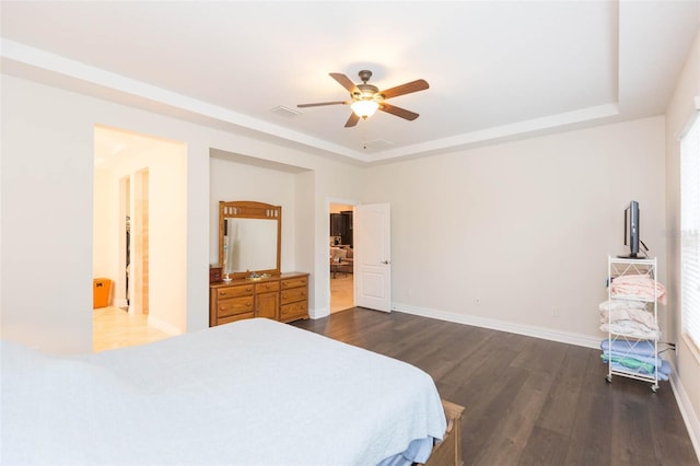 bedroom with visible vents, ceiling fan, baseboards, a tray ceiling, and dark wood-style floors