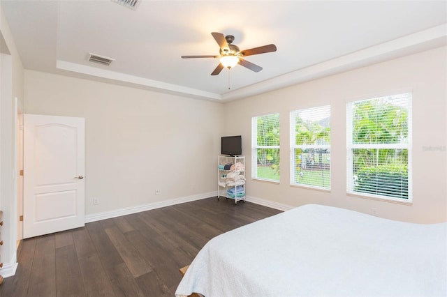 bedroom featuring a tray ceiling, baseboards, visible vents, and dark wood-style flooring