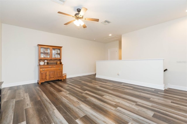 empty room with visible vents, ceiling fan, dark wood-type flooring, and baseboards