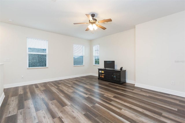 empty room with baseboards, dark wood-type flooring, and ceiling fan