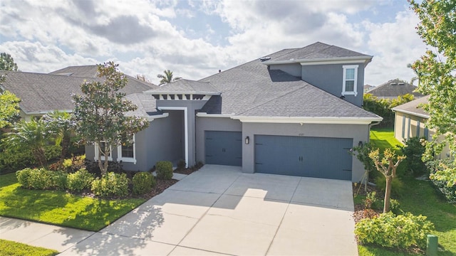 view of front of home with a garage, concrete driveway, a front yard, stucco siding, and a shingled roof