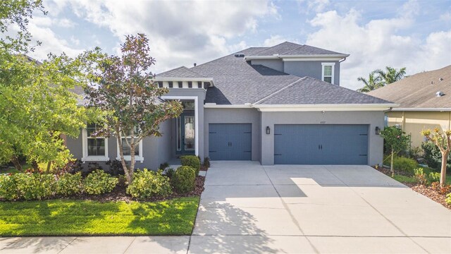 view of front of house featuring stucco siding, driveway, a garage, and a shingled roof