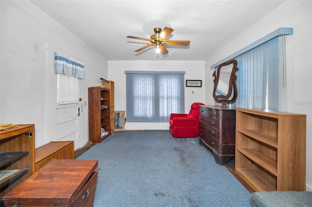 living area featuring carpet floors, ceiling fan, and ornamental molding