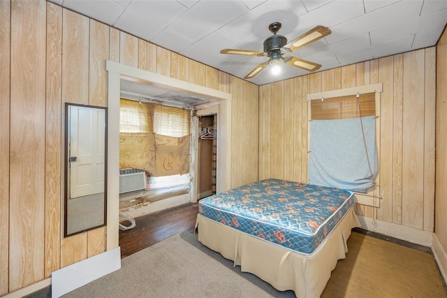 bedroom featuring a ceiling fan, wood walls, and a wall mounted AC