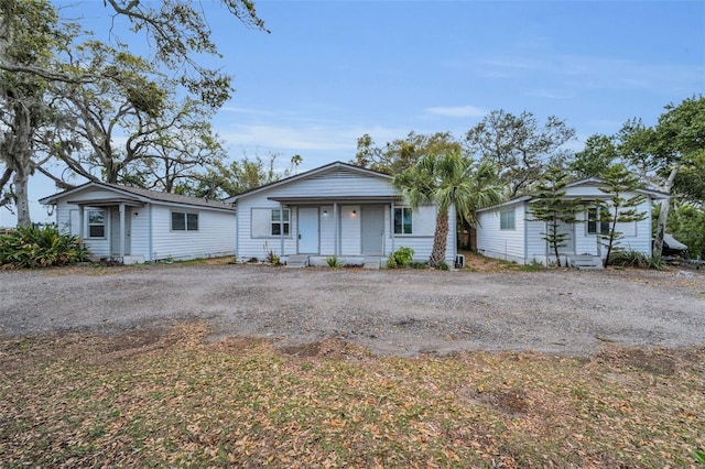 bungalow-style house featuring covered porch and dirt driveway