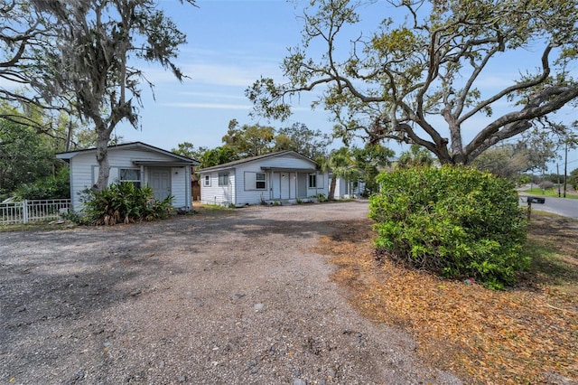 view of front of house with dirt driveway and fence