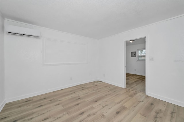 spare room with baseboards, light wood-style floors, an AC wall unit, and crown molding