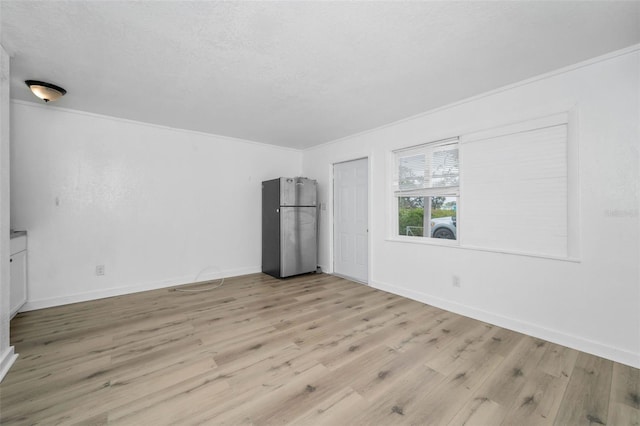 unfurnished room with ornamental molding, a textured ceiling, baseboards, and wood finished floors