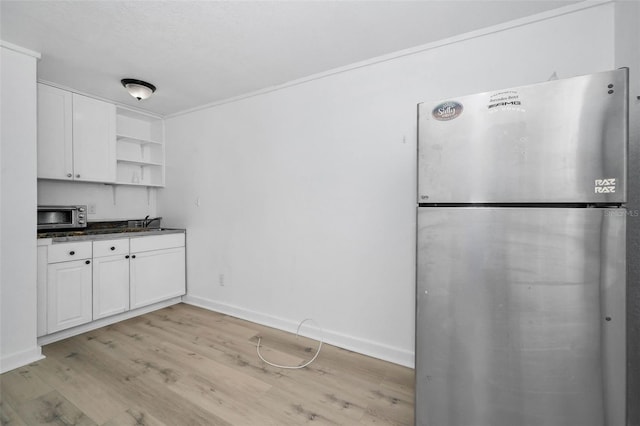 kitchen with white cabinetry, open shelves, dark countertops, and freestanding refrigerator