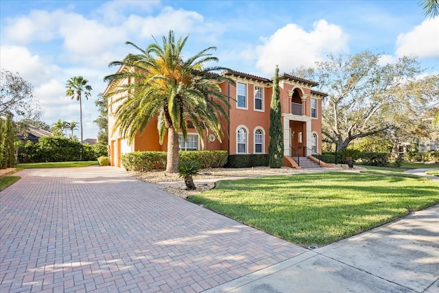 mediterranean / spanish house featuring a garage, decorative driveway, a front yard, and stucco siding