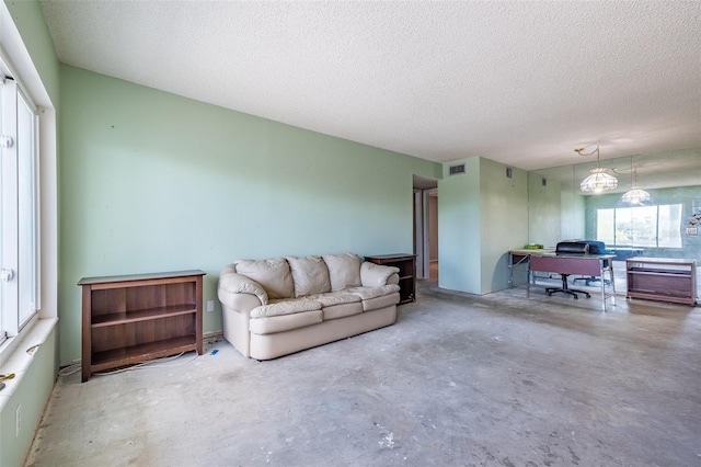 living room featuring visible vents, a textured ceiling, and concrete floors