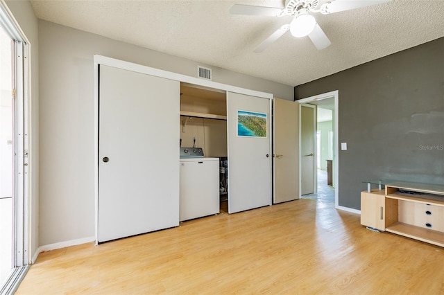 unfurnished bedroom with visible vents, washer / clothes dryer, light wood-style floors, and a textured ceiling