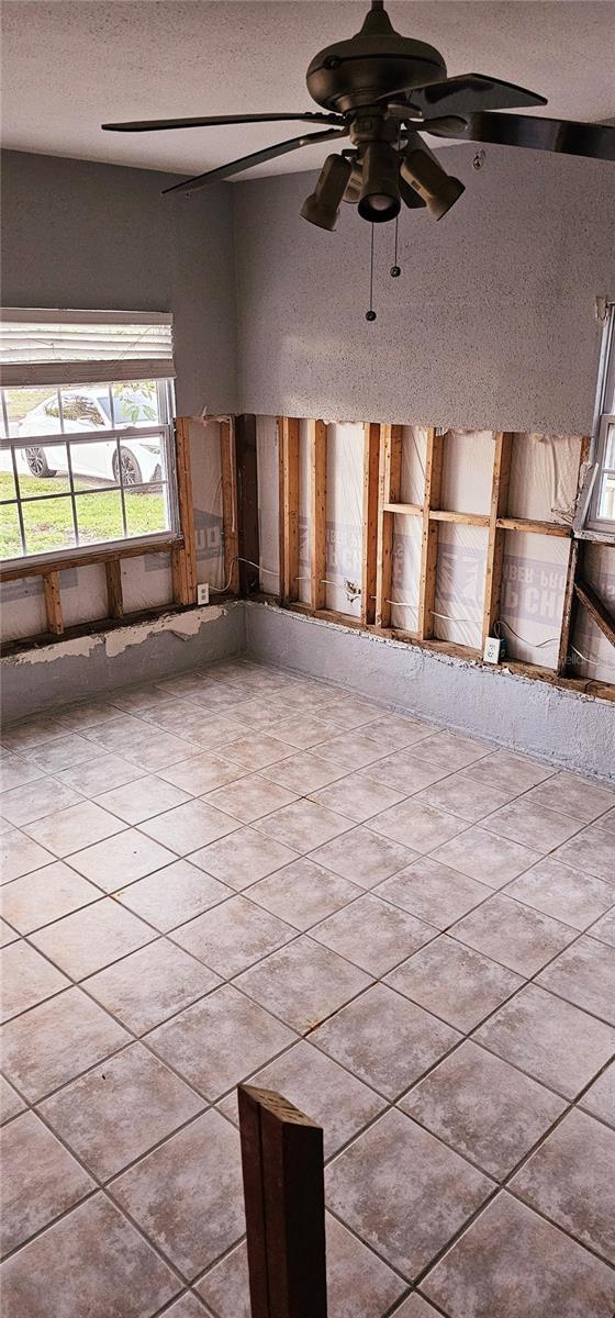 unfurnished room with a textured ceiling, ceiling fan, and tile patterned floors