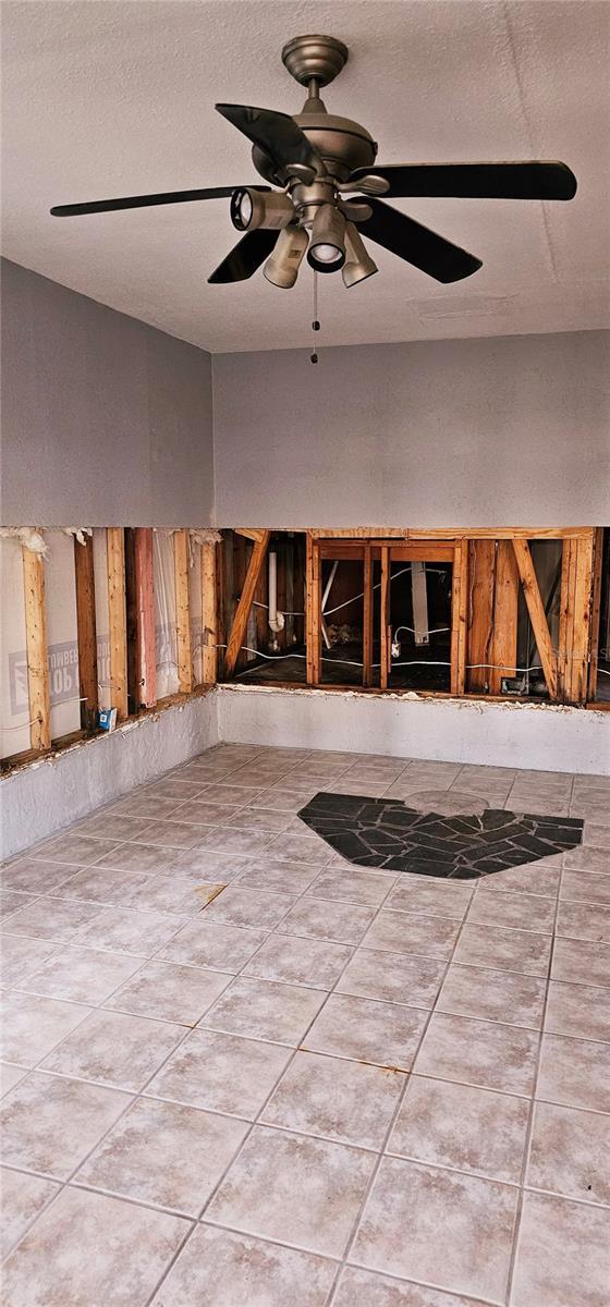 unfurnished room with a ceiling fan, vaulted ceiling, a textured ceiling, and tile patterned floors