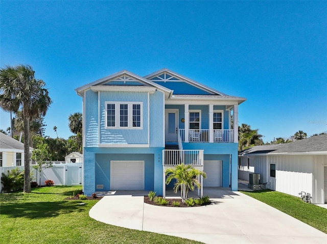 raised beach house featuring driveway, an attached garage, central AC, and a front yard