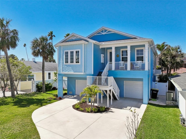 raised beach house with stairs, a porch, a garage, and a front yard