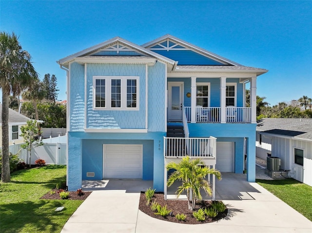 raised beach house featuring driveway, covered porch, a garage, and central AC