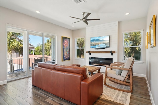 living area with visible vents, baseboards, recessed lighting, dark wood-style floors, and a glass covered fireplace