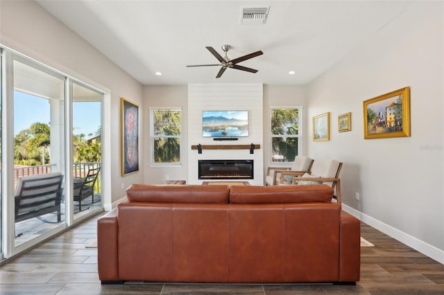 living area with dark wood finished floors, visible vents, a large fireplace, and baseboards