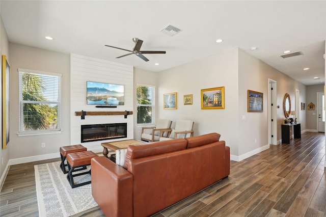 living room with dark wood-style floors, visible vents, baseboards, recessed lighting, and a fireplace