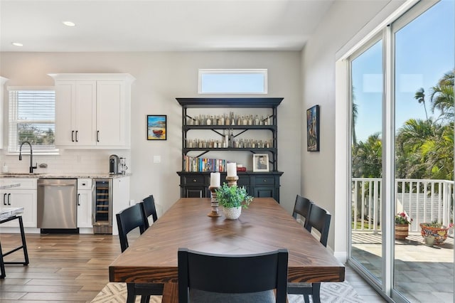 dining space featuring beverage cooler, recessed lighting, and wood finished floors