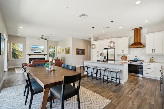 dining space featuring dark wood finished floors, recessed lighting, a fireplace, and visible vents