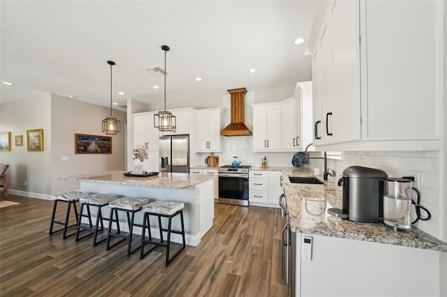 kitchen with a sink, a kitchen breakfast bar, a center island, appliances with stainless steel finishes, and custom exhaust hood