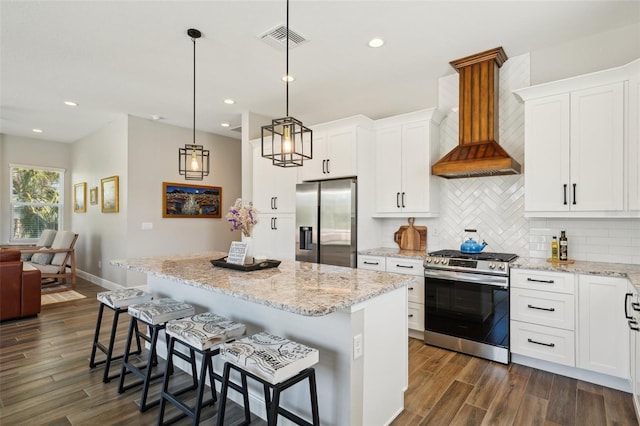 kitchen featuring visible vents, dark wood-type flooring, decorative backsplash, custom exhaust hood, and stainless steel appliances