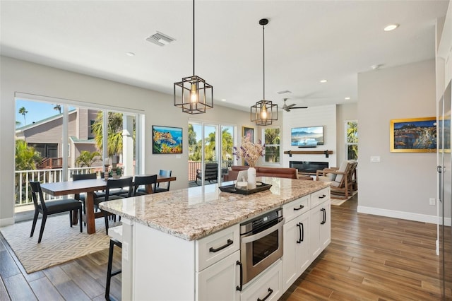 kitchen with visible vents, dark wood-style floors, white cabinetry, recessed lighting, and a large fireplace