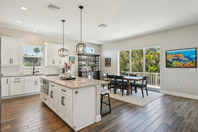 kitchen featuring a sink, visible vents, backsplash, and dark wood-style flooring