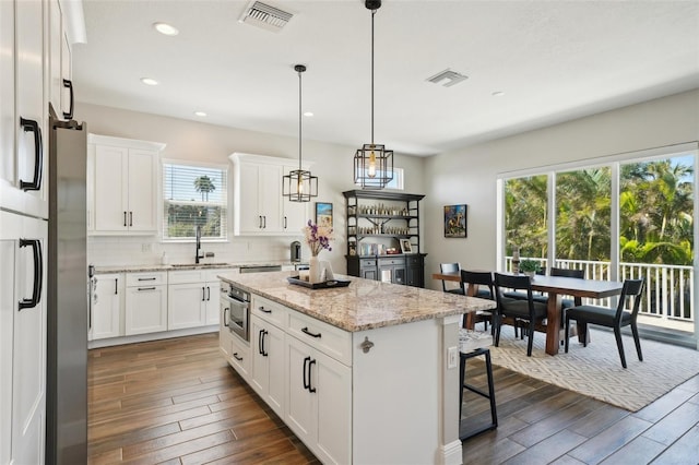 kitchen with decorative backsplash, visible vents, dark wood-style flooring, and a center island