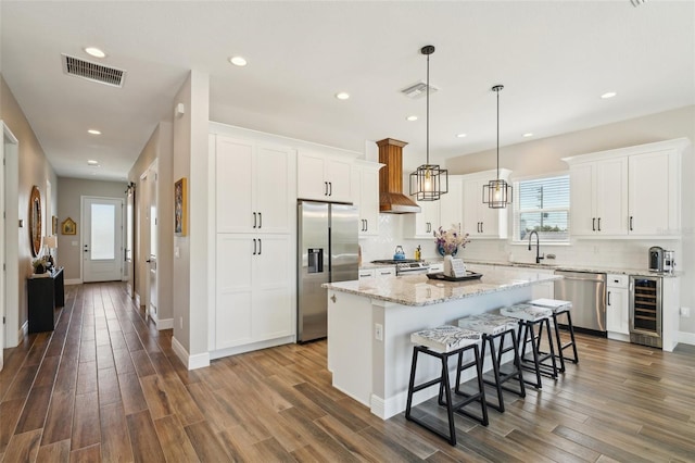 kitchen with visible vents, a sink, a kitchen island, stainless steel appliances, and wine cooler