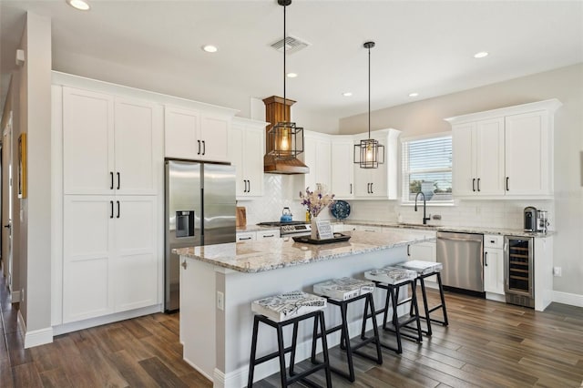 kitchen featuring visible vents, a sink, beverage cooler, appliances with stainless steel finishes, and dark wood-style flooring