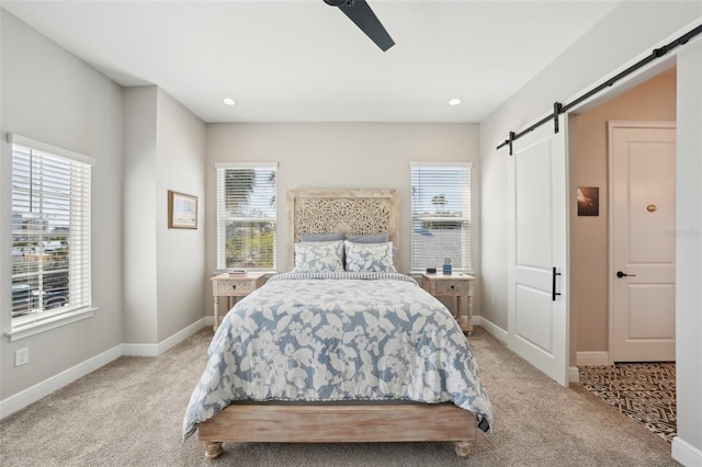 bedroom featuring light carpet, multiple windows, baseboards, and a barn door