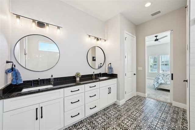 ensuite bathroom featuring baseboards, visible vents, ensuite bath, double vanity, and a sink