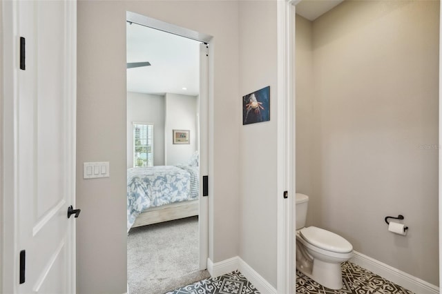 bathroom featuring baseboards, toilet, and ensuite bath