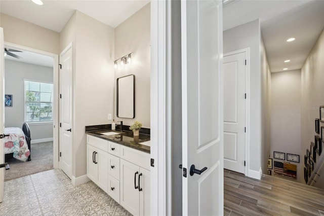 bathroom with baseboards, double vanity, recessed lighting, ensuite bath, and a sink