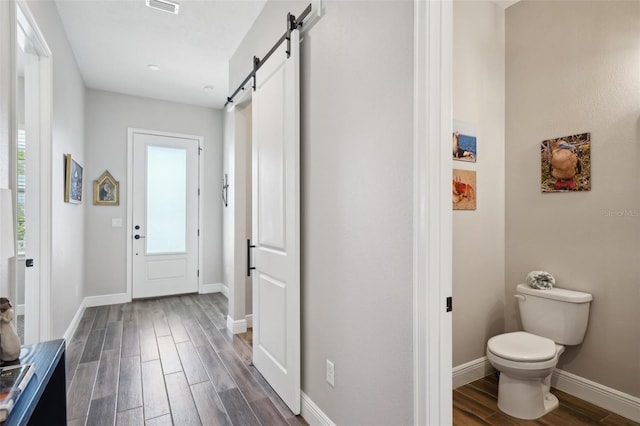 entryway with wood finish floors, a barn door, baseboards, and visible vents