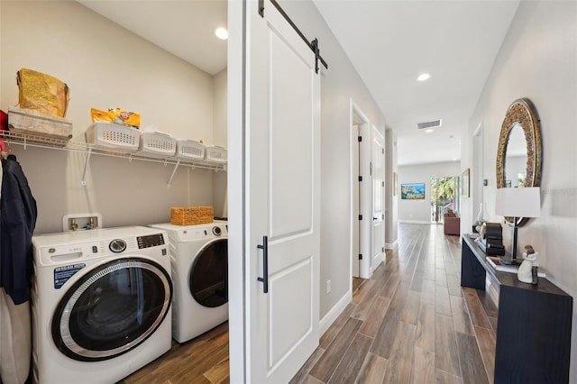 laundry room with wood finished floors, visible vents, laundry area, a barn door, and washer and clothes dryer