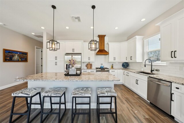720 Bay Esplanade, Clearwater Beach, FL 33767 - kitchen with stainless steel appliances, a sink, a kitchen bar, a center island, and white cabinetry