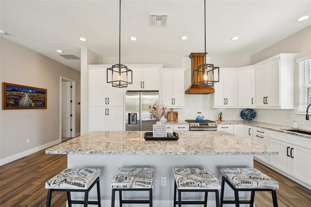 720 Bay Esplanade, Clearwater Beach, FL 33767 - kitchen with appliances with stainless steel finishes, backsplash, a center island, dark wood-style floors, and a breakfast bar