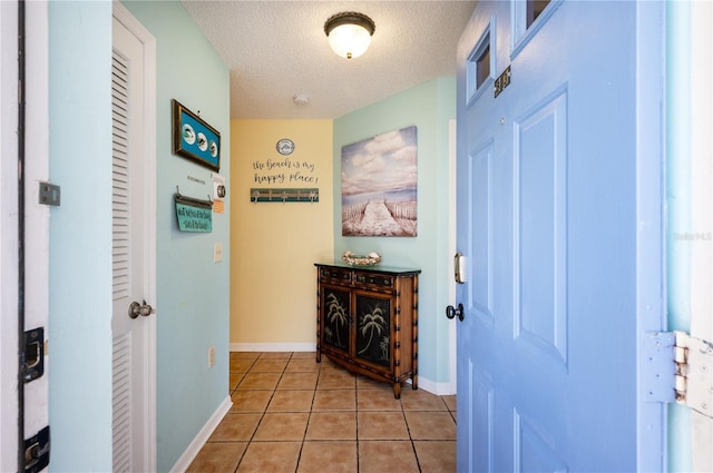 interior space with baseboards, a textured ceiling, and light tile patterned flooring