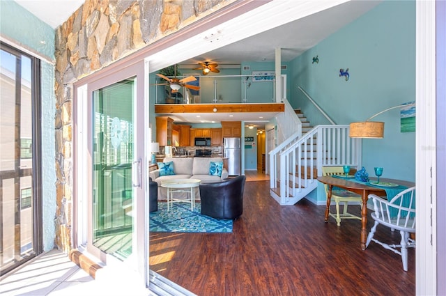 interior space with stairs, a high ceiling, wood finished floors, and ceiling fan