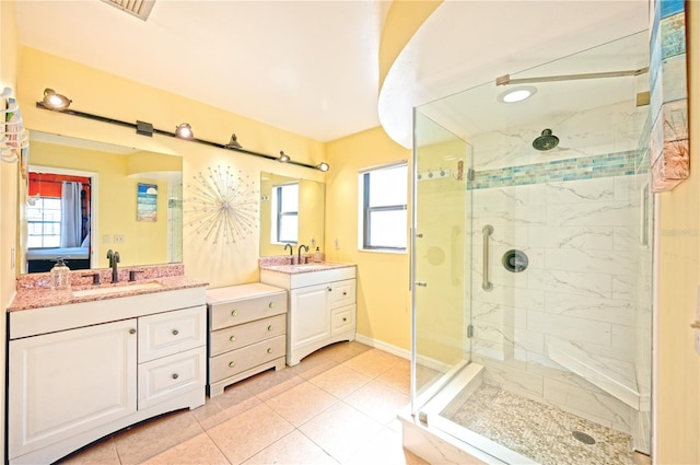 full bath with tile patterned floors, two vanities, a sink, a shower stall, and baseboards