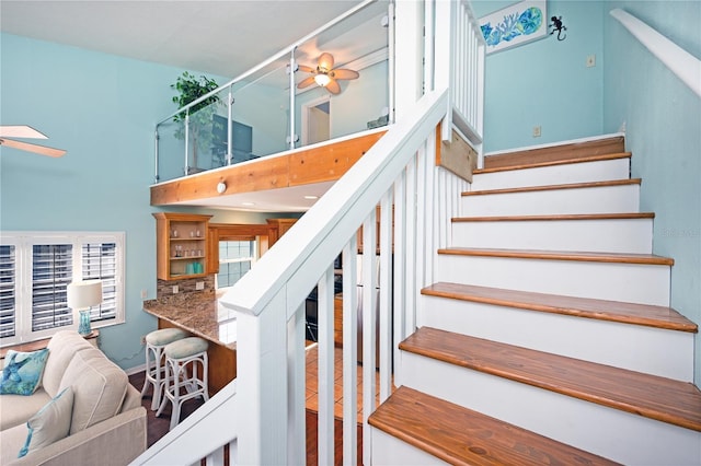 stairway featuring a high ceiling and ceiling fan