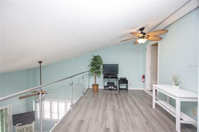 interior space featuring a ceiling fan, vaulted ceiling, wood finished floors, and baseboards